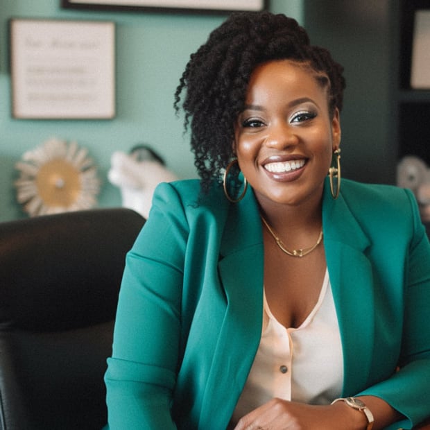 A manifestation coach seated, looking at the camera